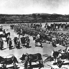 Soldaten und Pferde versammeln sich vor einem Turm. Die Szene erinnert an die Schlacht am Waterberg, ein entscheidendes Ereignis in der Kolonialgeschichte.