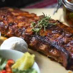 Un ribs de porc laqué, garni de romarin, avec une sauce barbecue, de l'ail et une salade fraîche.