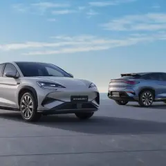 Dwa nowoczesne SUV-y marki BYD, jedne z wielu chińskich marek samochodów, prezentują się na tle błękitnego nieba i morza.