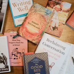 Une pile de livres sur une table en bois, parfaite pour un podcast littéraire. On y trouve des biographies, des essais et des romans.