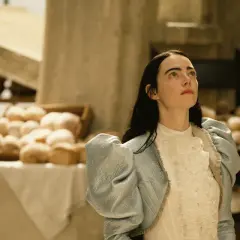 Bella Baxter blickt hoffnungsvoll gen Himmel, während sie auf dem Markt steht. Ein Bild, das Lust macht, "Poor Things" zu streamen.