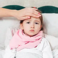 Bambina a letto con sciarpa rosa, mano sulla fronte per controllare la febbre, forse la quarta malattia.