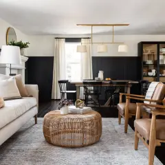 A living and dining space with a neutral palette and natural textures, embodying the mcgee and co style. A light-colored sofa, rattan coffee table, and leather armchairs create a cozy seating area.