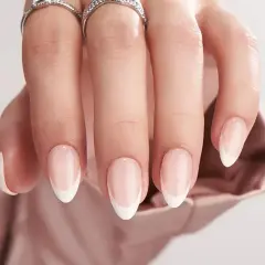 En hand med eleganta, korta french naglar och två glittrande ringar.