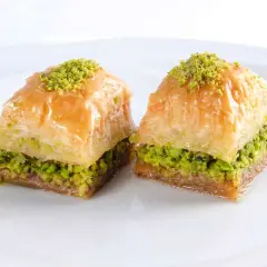 Zwei süße, schichtweise gebackene Teigstücke mit Pistazienfüllung und Sirup. Das ist Baklava, ein köstliches Dessert.