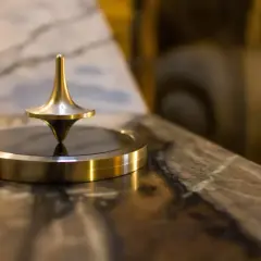 Toupie dorée en rotation, un exemple de force centrifuge qui maintient son équilibre.