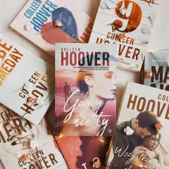 Książki Colleen Hoover ułożone na jasnym tle, ozdobione światełkami i sztucznymi kwiatami. Wśród nich "Gdyby nie ty", "Maybe Someday" i "Wszystkie nasze obietnice".