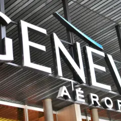 Napis "GENEVE AEROPORT" na tle nowoczesnej architektury, symbolizujący jedne z wielu lotnisk w Szwajcarii.