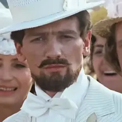 Mężczyzna w białym cylindrze i garniturze, jak z filmu "Noce i dnie", z wąsami i bródką.