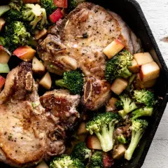 Juicy miso pork chops with roasted broccoli and apple chunks in a cast iron skillet.