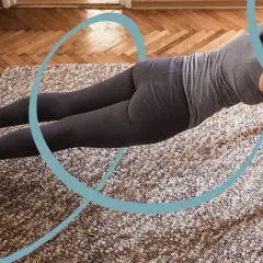 Kobieta w pozycji deski wykonuje jedno z 5 ćwiczeń pilates. Obok leżą hantle.