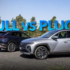 Confronto tra full hybrid modelli: un uomo indica due Hyundai Tucson, una blu e una grigia, sotto la scritta "FULL VS PLUG-IN".