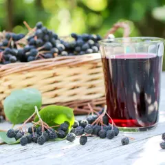 Aronia w koszyku i szklanka nalewki. To przepis babci na nalewkę z aronii, idealny na jesienne wieczory.