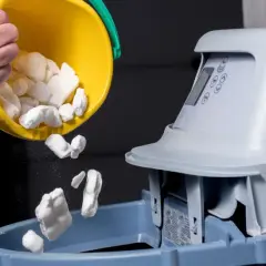 Une personne verse des pastilles de sel dans un système adoucisseur d'eau.
