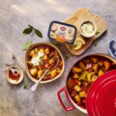 Herzhaftes Gulasch mit Kartoffeln und Paprika, perfekt zum Schmoren lassen. Daneben ein Becher Schmalz und Gewürze.