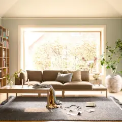Gemütliches Wohnzimmer mit braunem Sofa, Bücherregal und Kamin. Tolle Sofa Ideen für wenig Platz, die Gemütlichkeit schaffen.