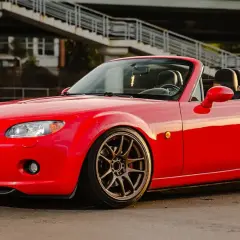 Mazda MX-5 rouge rutilante, parfaite pour un jeune permis rêvant de sa première voiture sport.