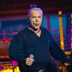 Bruce Dickinson, wokalista Iron Maiden, śpiewa z mikrofonem na koncercie.