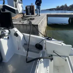 En vit båt vid en brygga. Vattnet är klart och man kan se alger i diesel-färgat vatten.
