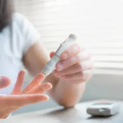 Kobieta wykonuje pomiar glukozy glukometrem. Dba o swoje zdrowie i **viglita** dzięki regularnym badaniom.
