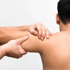 Fizjoterapeuta bada ramię pacjenta, szukając przyczyny bólu. Zapalenie stawu barkowego jak długo trwa, zależy od wielu czynników.