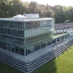 Moderner Glasbau der Hochschule Friedrichshafen mit angrenzendem Campus und Wald.
