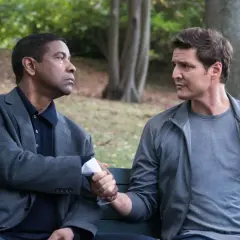 Denzel Washington i Pedro Pascal, obsada "Bez litości 2", ściskają sobie dłonie na ławce w parku.