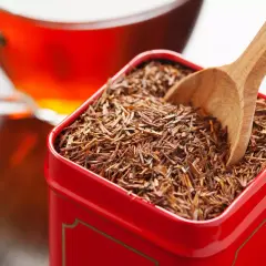 Czerwona herbata rooibos w metalowym pudełku, gotowa do zaparzenia. Bez kofeiny, idealna na relaks.