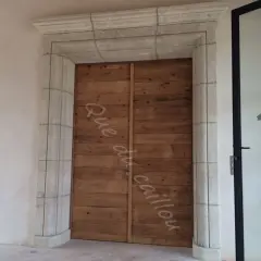 Un encadrement de porte en pierre, avec une couleur différente de la porte en bois brut.