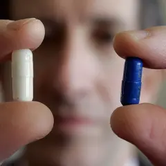 Dita tengono una pillola bianca e una blu, forse per uno studio sull'effetto placebo.