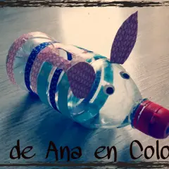 Hucha de hucha manualidades hecha con botella, decorada con cintas de colores y ojos saltones. ¡Un cerdito divertido!