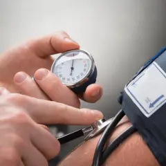 Lekarz mierzy ciśnienie krwi pacjentowi. Manometr wskazuje wynik, a stetoskop jest gotowy do osłuchania. To ważny element kontroli zdrowia, jak np. przy stosowaniu leku Triplixam.
