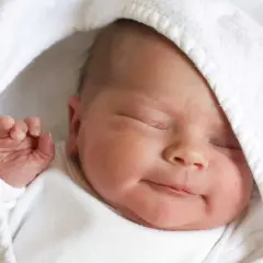 La morbida pelle neonato, avvolta in un soffice asciugamano bianco, dorme serenamente.