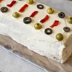 Pastel frío de atún decorado con aceitunas y pimientos rojos.