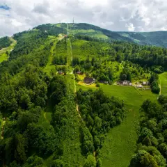 Widok z lotu ptaka na zielone zbocza Skrzycznego z kolejką linową i domkami.