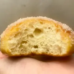 Gros plan d'un beignet sucré, sa mie aérée parfaite pour une recette beignet maison.