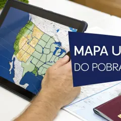 Osoba planuje podróż, przeglądając na tablecie mapę, która pokazuje, gdzie leżą Stany Zjednoczone. Obok leży paszport.