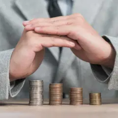 Ręce nad stosami monet, symbolizujące bezpieczeństwo finansowe. Dowiedz się, gwarancja bankowa jak uzyskać.