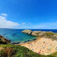 Vista aérea de la playa de Somo, con gente disfrutando del sol y el mar. Las reseñas de la playa de Somocuevas la describen como un paraíso.