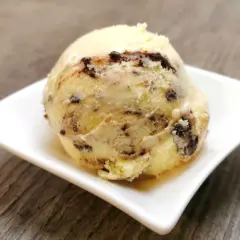 Ein cremiges Eis mit Schokoladenstückchen, das an Cookies erinnert, auf einer weißen Schale.