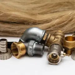 Różnorodne złączki hydrauliczne i zawory odcinające, obok pęczka lnianego sznurka.