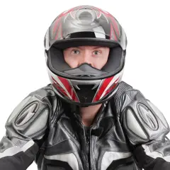 Occhi spalancati dietro un casco stretto, pronto per la corsa. La tuta in pelle grigia e nera completa il look da motociclista.