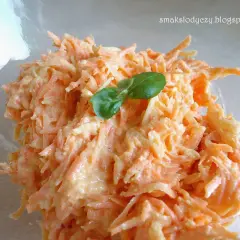 Pyszna surówka z marchewki z chrzanem, doprawiona i udekorowana listkiem bazylii. Idealna na wiosenny obiad.