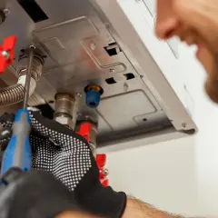 Tecnico con guanti lavora su caldaia Baxi in blocco, cercando di sbloccarla con un cacciavite.