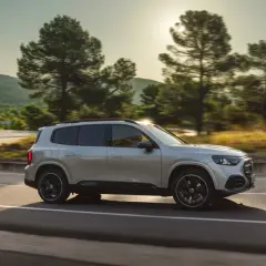 Nowy Mercedes GLB sunie po krętej drodze wśród drzew.