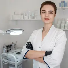 Młoda kosmetolog w gabinecie, gotowa do zabiegu. W tle sprzęt i kosmetyki.