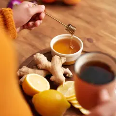 Zutaten für hustentee selber machen: Ingwer, Zitrone, Honig und eine Tasse Tee.