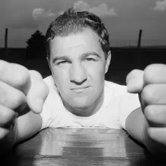 A determined boxer, perhaps a 49-0 legend, leans forward, fists clenched and ready.