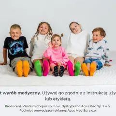 Pięcioro dzieci siedzi na podłodze, prezentując kolorowe skarpetki na stopach.