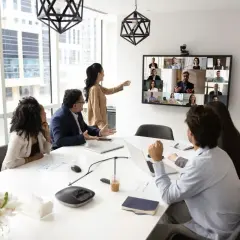 Ein Team im Büro nimmt an einer Videokonferenz teil, was zeigt, was ist hybrides arbeiten: Präsenz und Remote-Teilnehmer vereint.